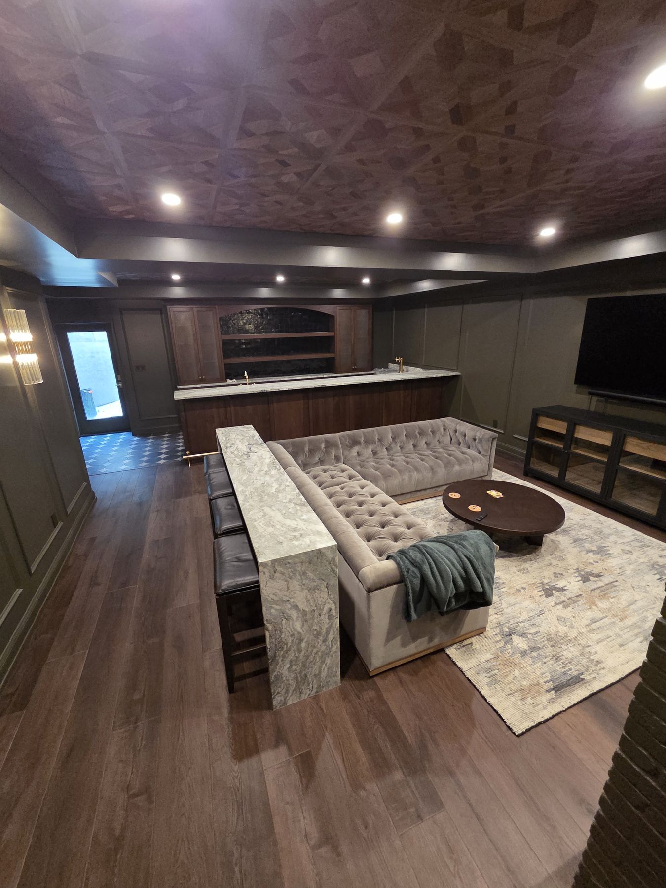 Home 1 Finished basement lounge with dark painted walls and paneled ceiling