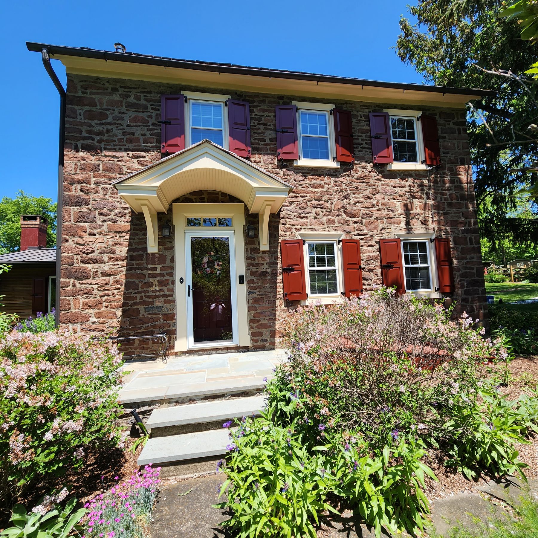 Stone colonial with freshly painted trim, door, and shutters